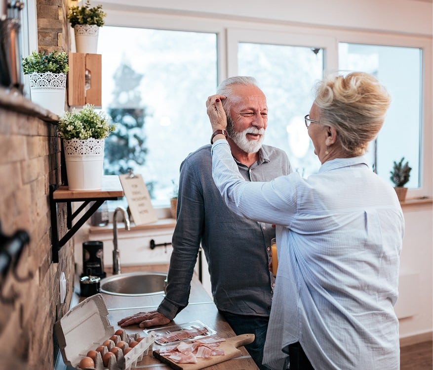 Senior couple in a kitchen preparing food together, representing senior real estate specialist support for downsizing in the Northwest Suburbs of Chicago